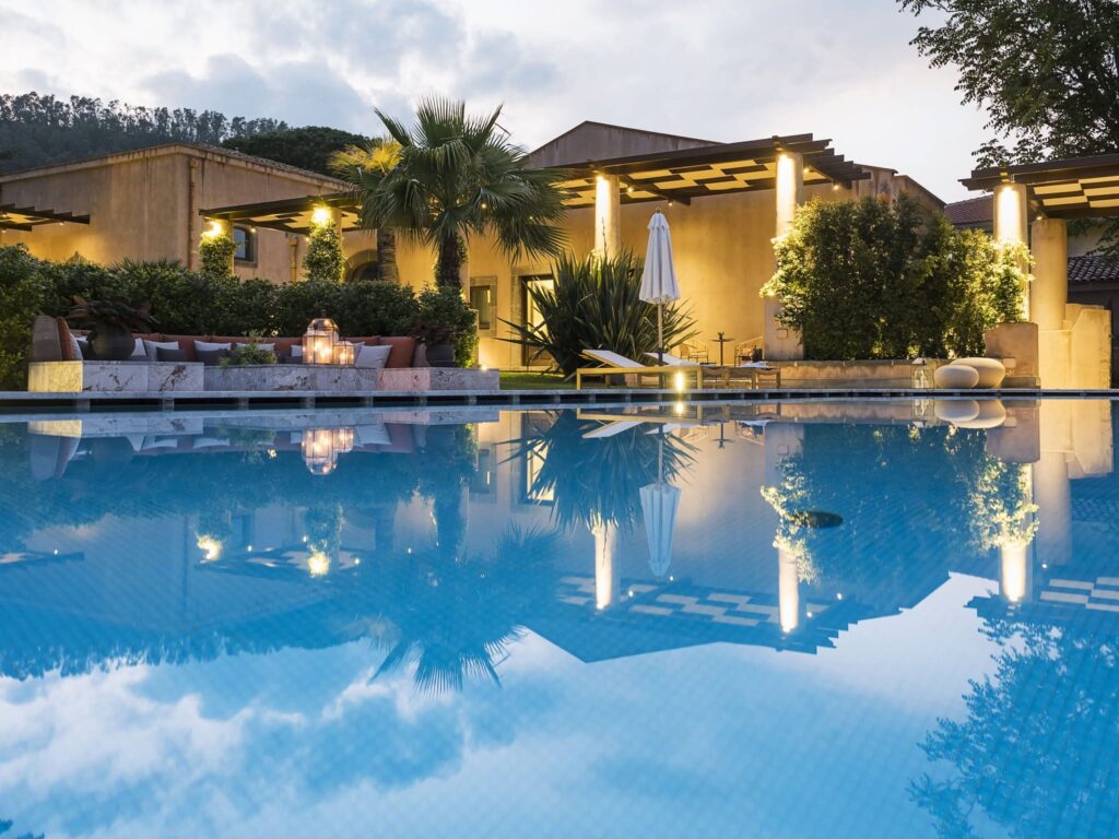 Piscina do Relais San Giuliano, uma referência de lazer entre os hotéis boutique na sicilia, refletindo o crepúsculo.