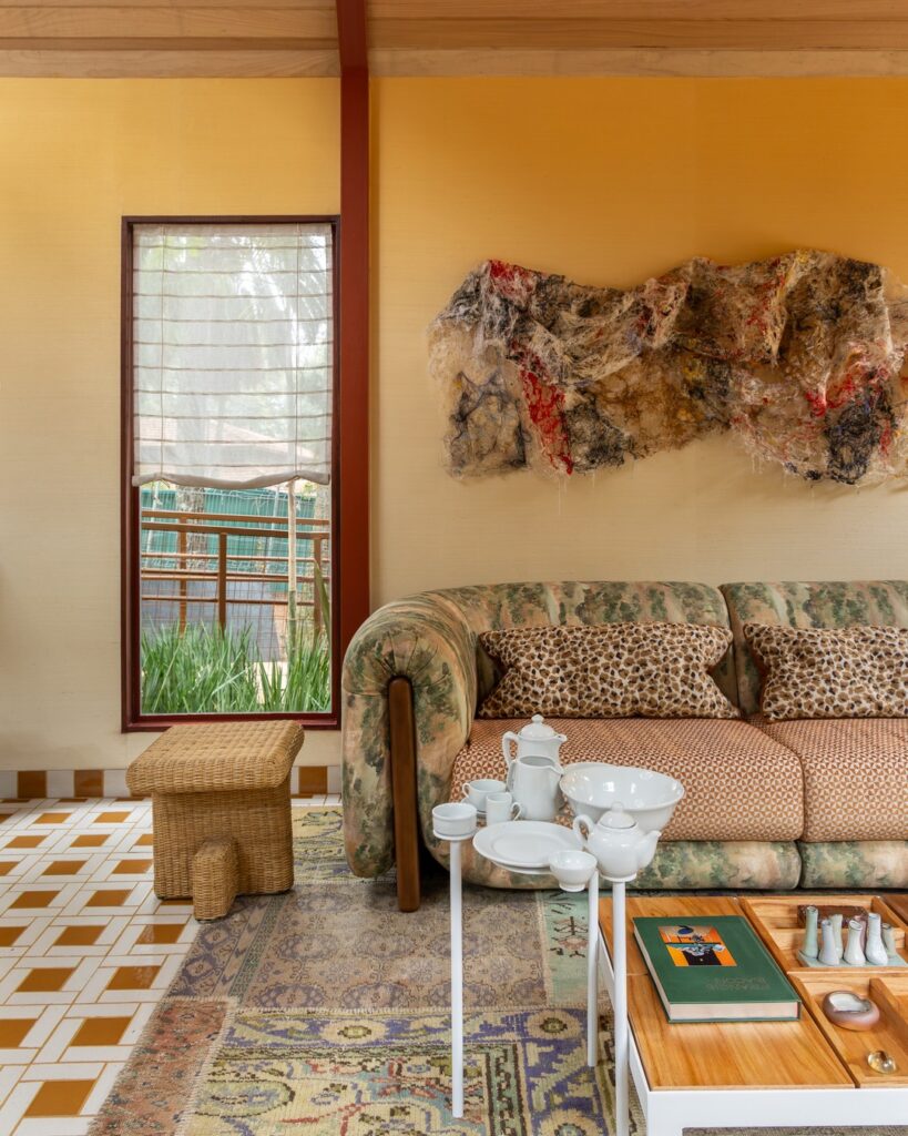 Sala de estar com sofá curvo estofado e mesas de centro artesanais na Casa EcoMorada, projeto da Volar Interiores na CasaCor 2026.