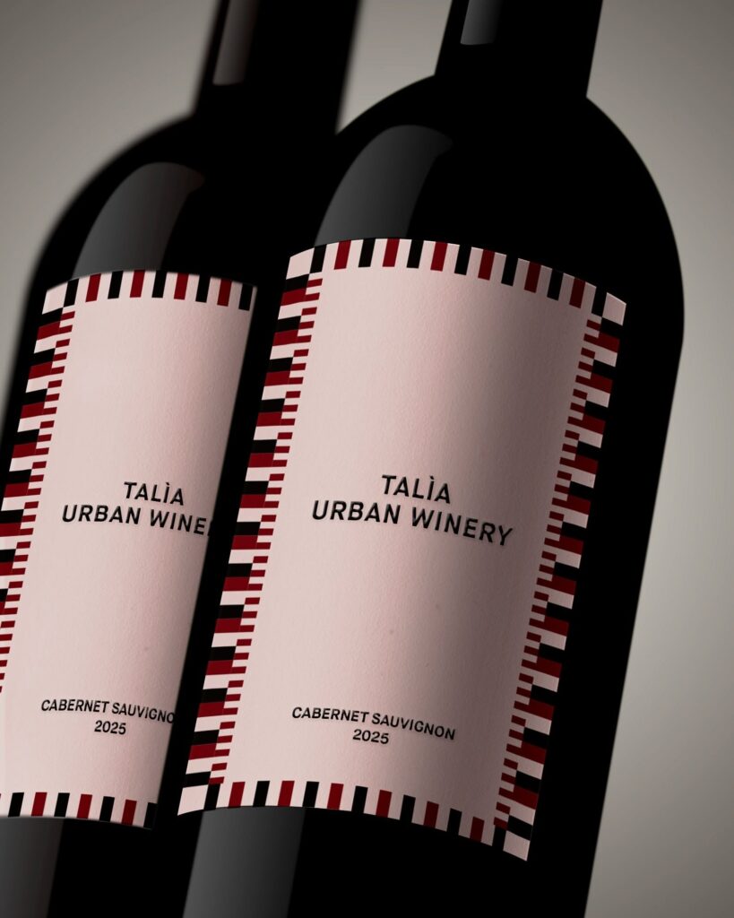 Duas garrafas de vinho tinto com rótulo de bordas geométricas da marca própria do hotel Palazzo Talìa em Roma.