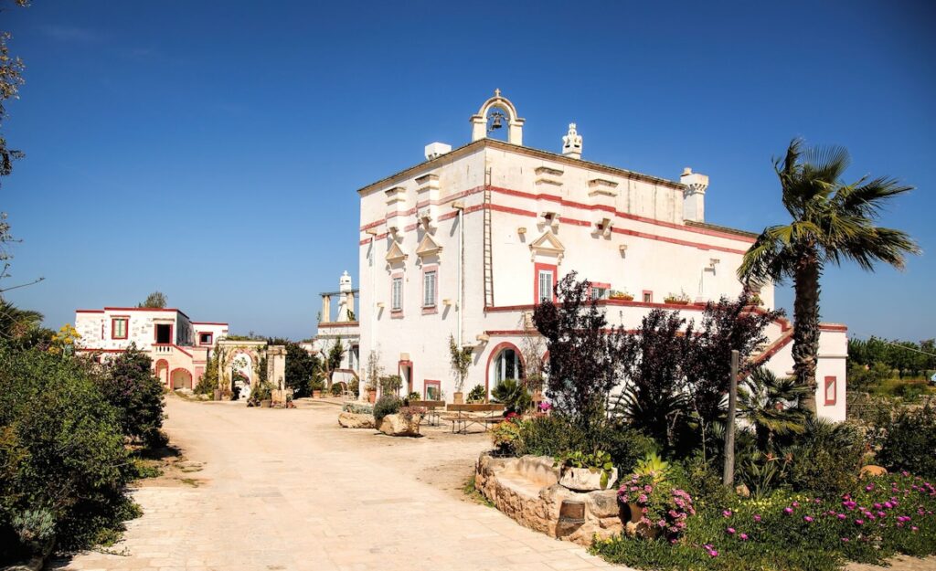 Fachada histórica caiada de branco com detalhes em terracota na Masseria Montenapoleone.