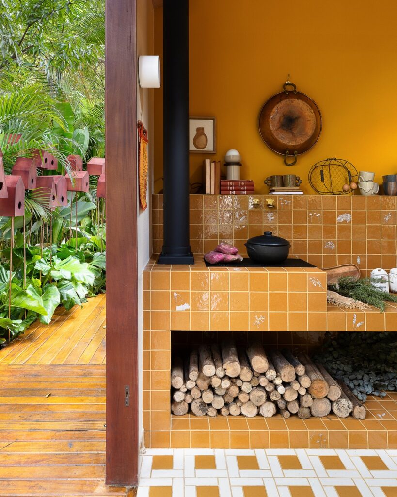 Fogão a lenha revestido de azulejo terracota integrado ao deck externo na Casa EcoMorada por Volar Interiores na CasaCor 2026.