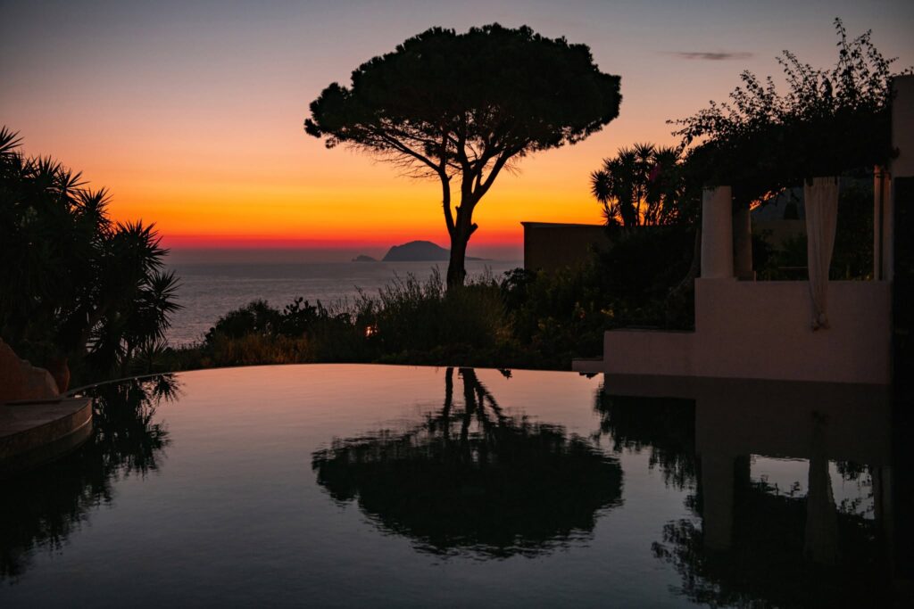 Pôr do sol espelhado na piscina infinita do Hotel Signum Salina, destaque entre os hotéis boutique na sicilia.