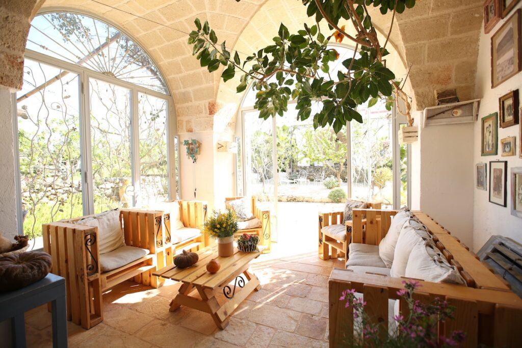 Lounge abobadado com sofás de palete de madeira e grandes janelas na Masseria Montenapoleone.