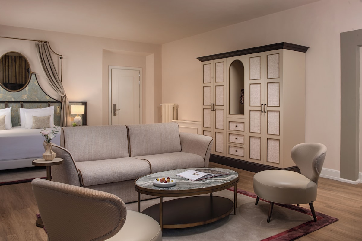 Torrigiani Junior Suite no Porta Rossa, ampla sala de estar com sofá bege claro contemporâneo, mesa oval de mármore e armário com portas de palhinha.