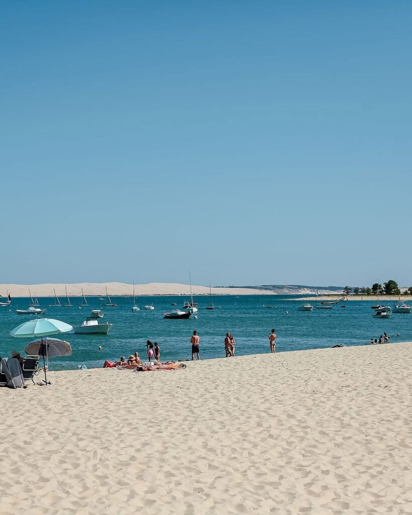 Vista da praia de Cap Ferret com barcos ancorados na Bacia de Arcachon e a Dune du Pilat ao fundo, próxima ao hôtel villa colette.