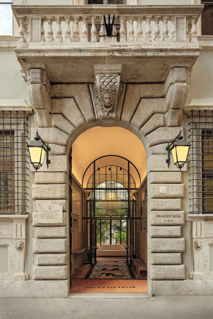 Entrada monumental de pedra com arco histórico e placas de identificação do hotel Palazzo Talìa em Roma.