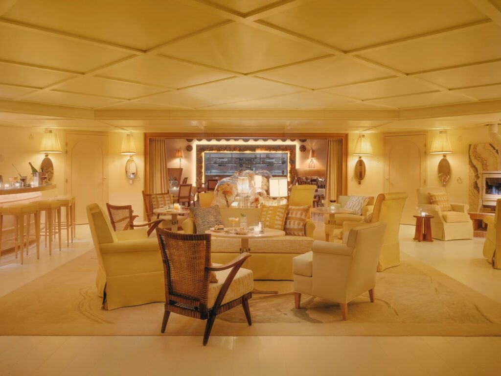 Lounge bar do hôtel villa colette com poltronas amarelas, lareira acesa e iluminação cenográfica aconchegante ao anoitecer.
