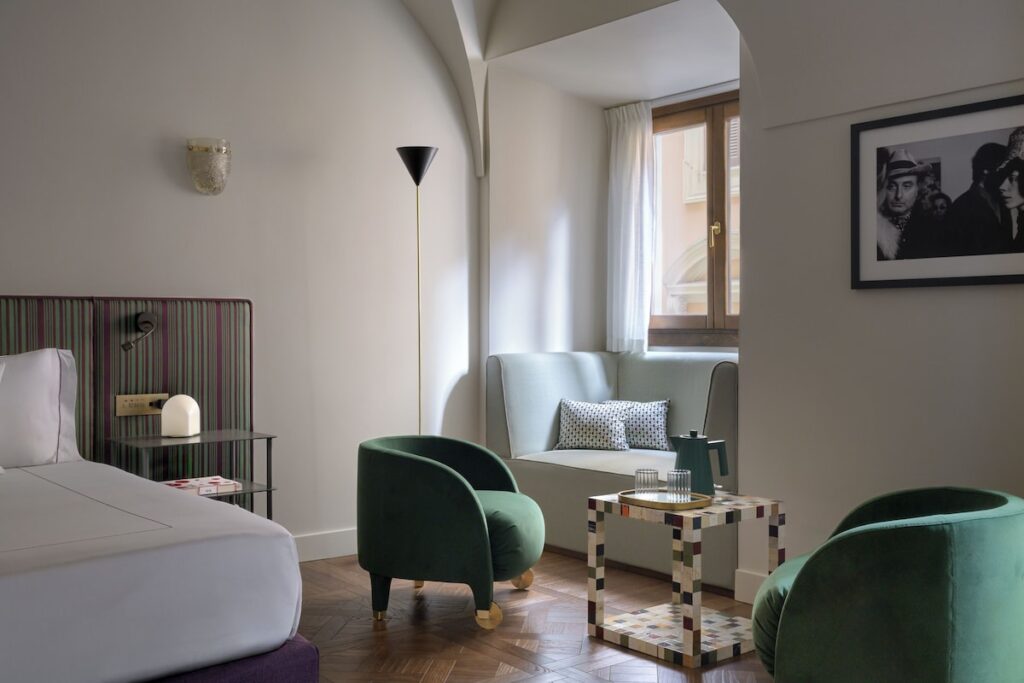 Poltronas de veludo verde e mesinha de mosaico na área de estar da Suíte Junior do hotel Palazzo Talìa Roma.