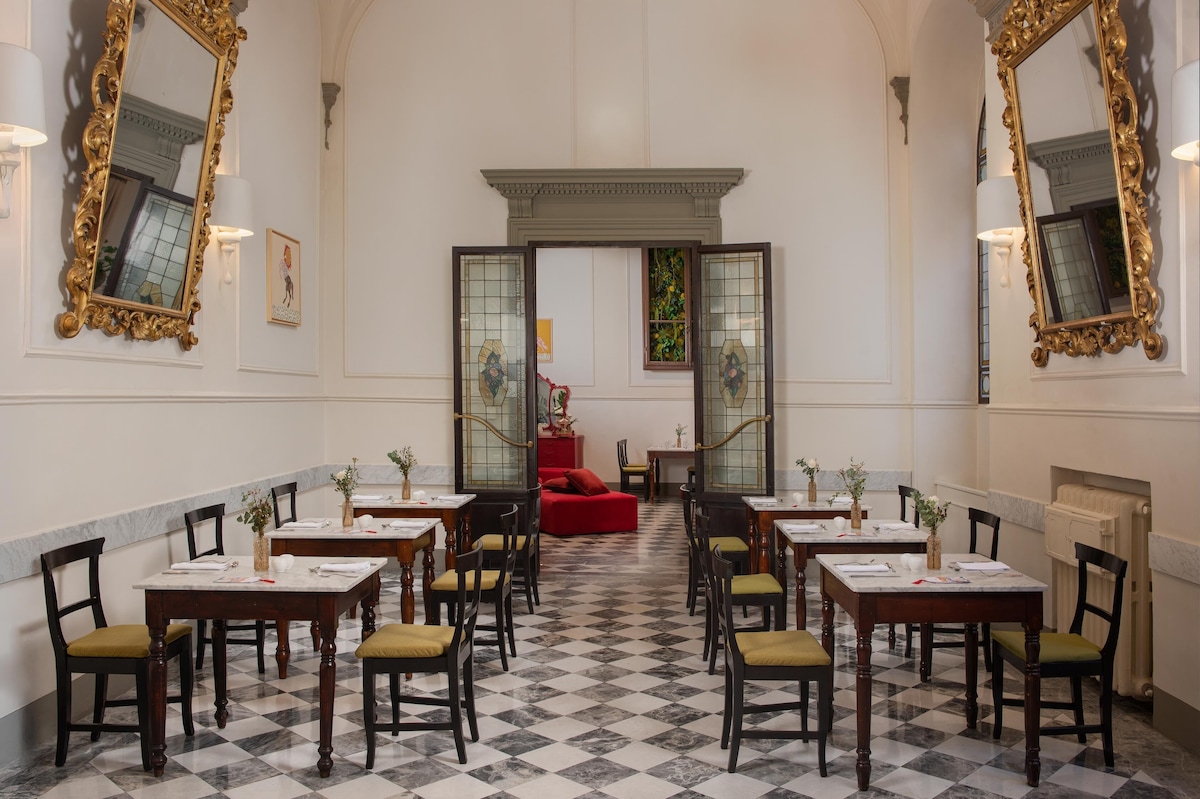 Salão do Restaurante no Porta Rossa com piso de mármore xadrez, mesas bistrô com tampos de mármore, grandes espelhos rococó e portas de vitrais antigos.