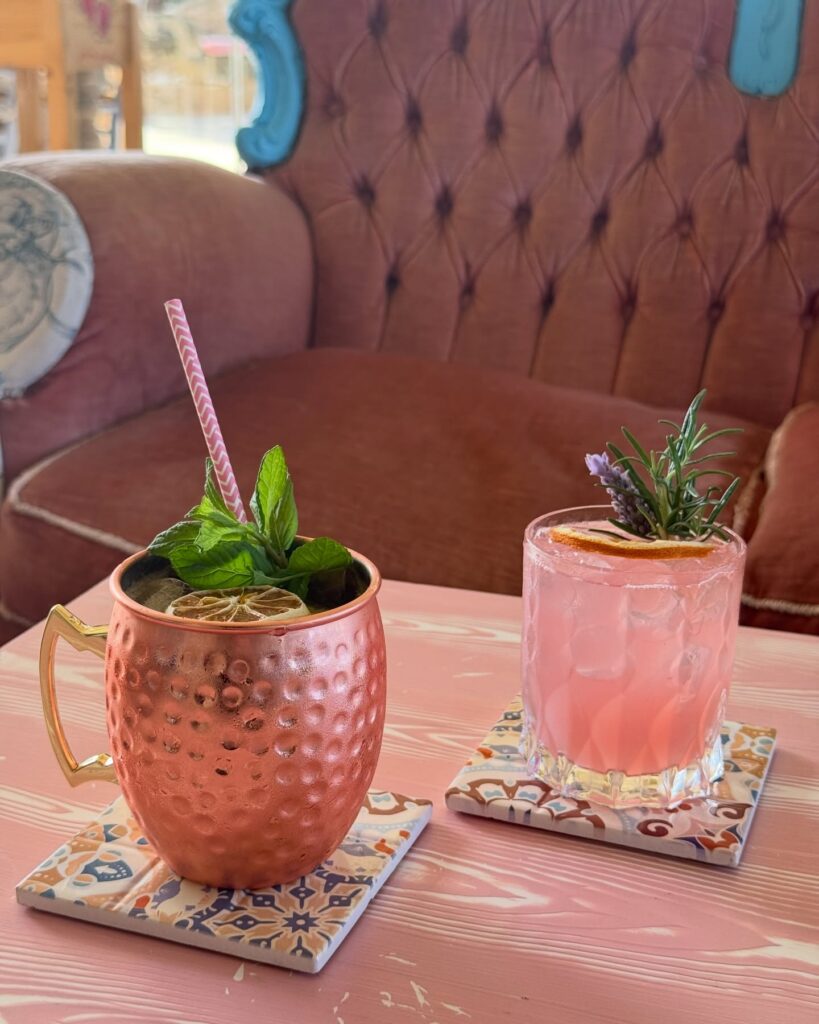 Drinks artesanais decorados com ervas frescas em mesa rosa na Masseria Montenapoleone.