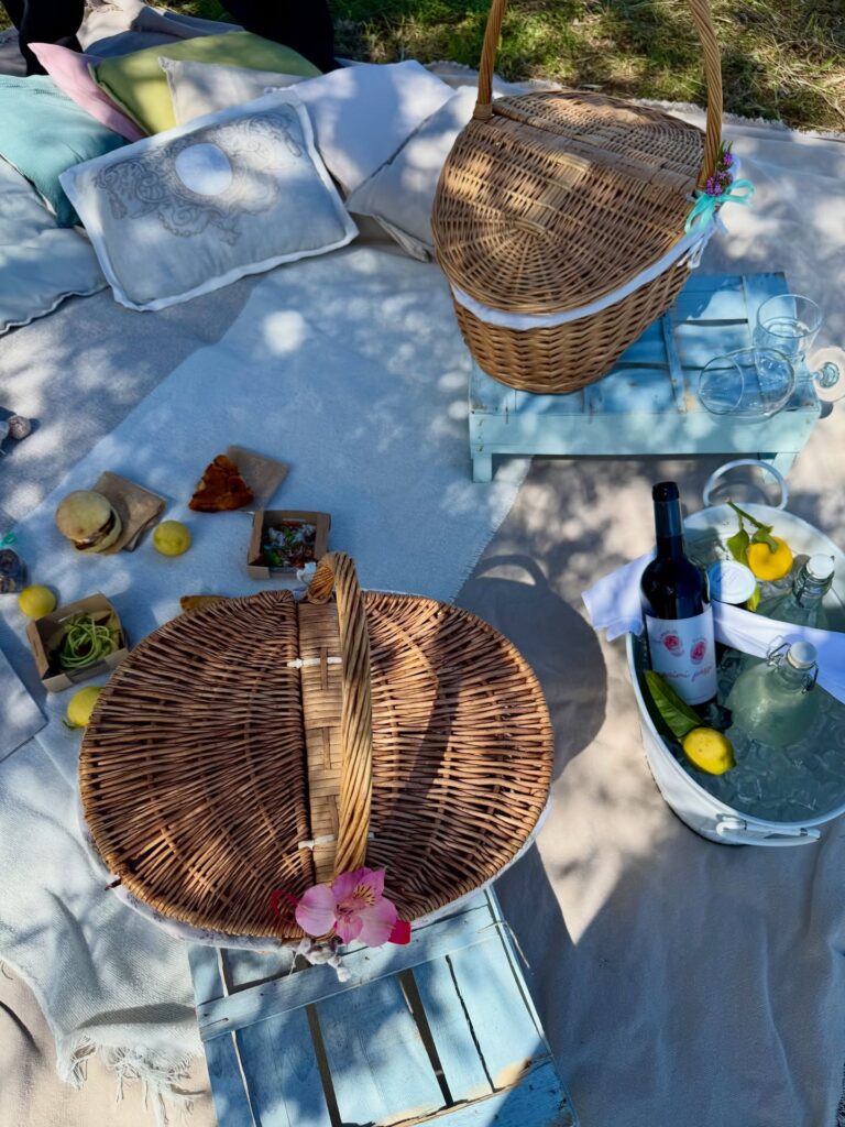 Piquenique no jardim com cestos de vime e vinho orgânico na Masseria Montenapoleone.