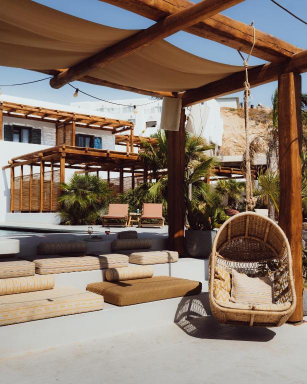 Lounge externo em degraus com balanço de vime e pérgula de madeira no Branco Mykonos, refúgio de onde ficar em Mykonos.