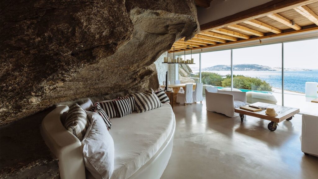 Suíte com rocha natural integrada e vista para o mar no Cavo Tagoo, referência de luxo sobre onde ficar em Mykonos.