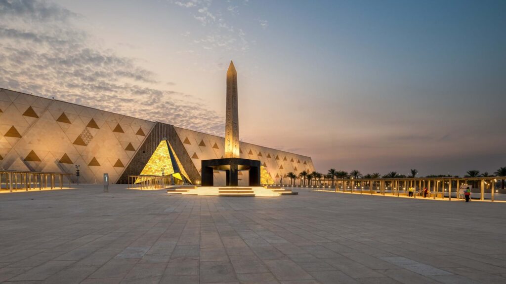 Fachada monumental em alabastro translúcido e praça com obelisco suspenso no Grand Egyptian Museum em Gizé.