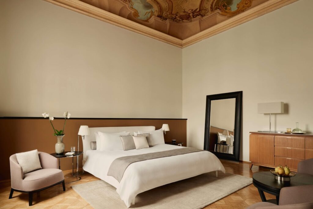 Suíte minimalista do Aman Venice com afresco histórico e mobiliário contemporâneo, ícone entre os hotéis de Veneza.