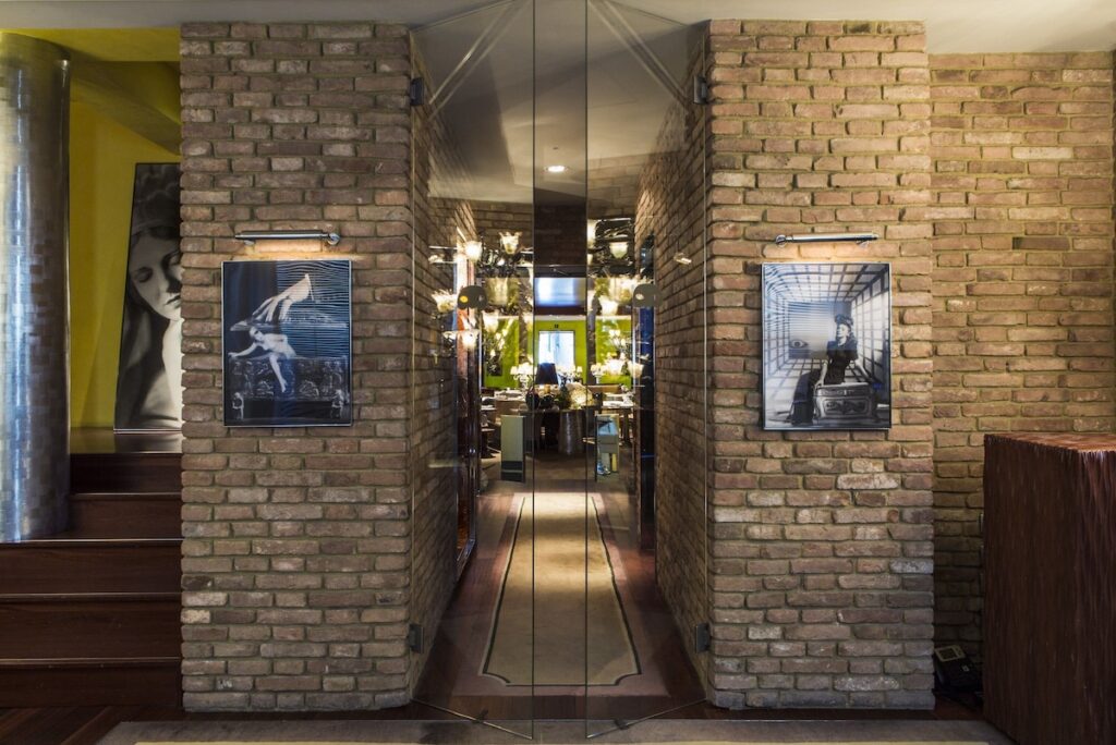 Entrada com paredes de tijolos aparentes e fotografias de arte no Palazzina Grassi, vanguarda nos hotéis de Veneza.