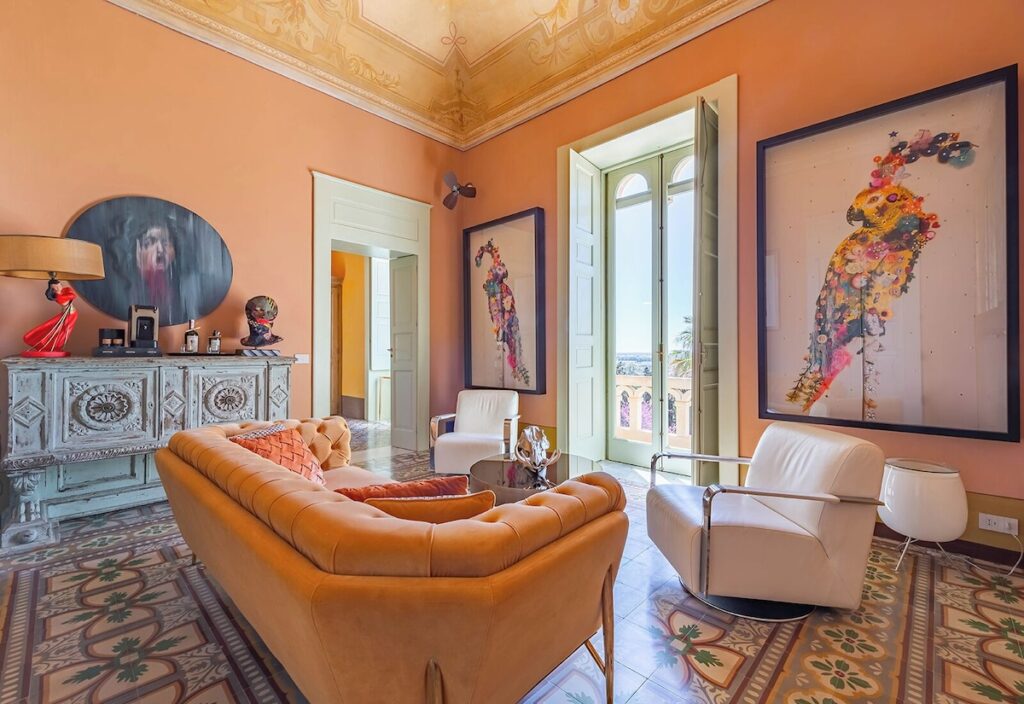 Sala de estar em suíte do Castle Elvira com afrescos originais, sofás de veludo e piso em cementine, referência entre hotéis boutique na Púglia.
