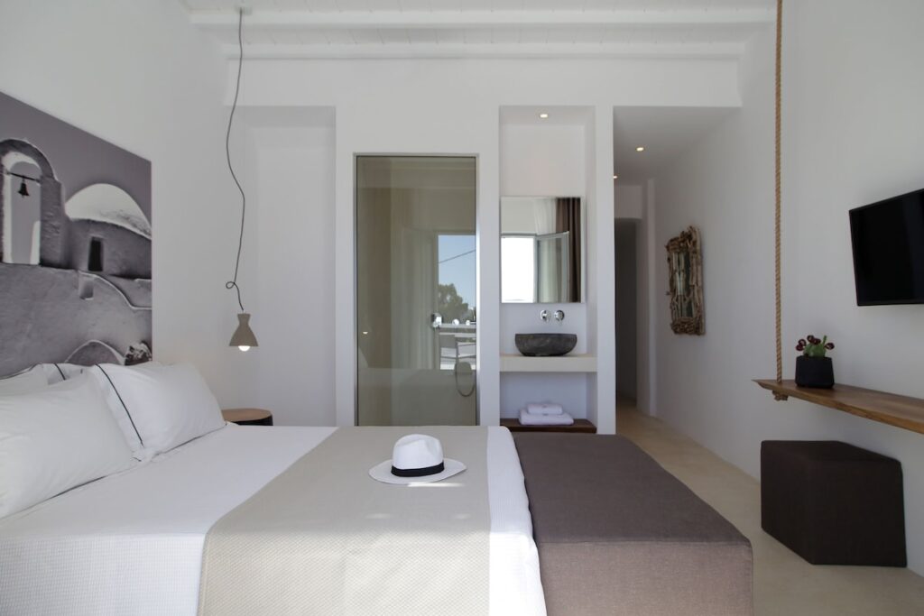 Suíte minimalista com bancada em pedra esculpida e teto em vigas no Livin Mykonos Hotel, opção de onde ficar em Mykonos.