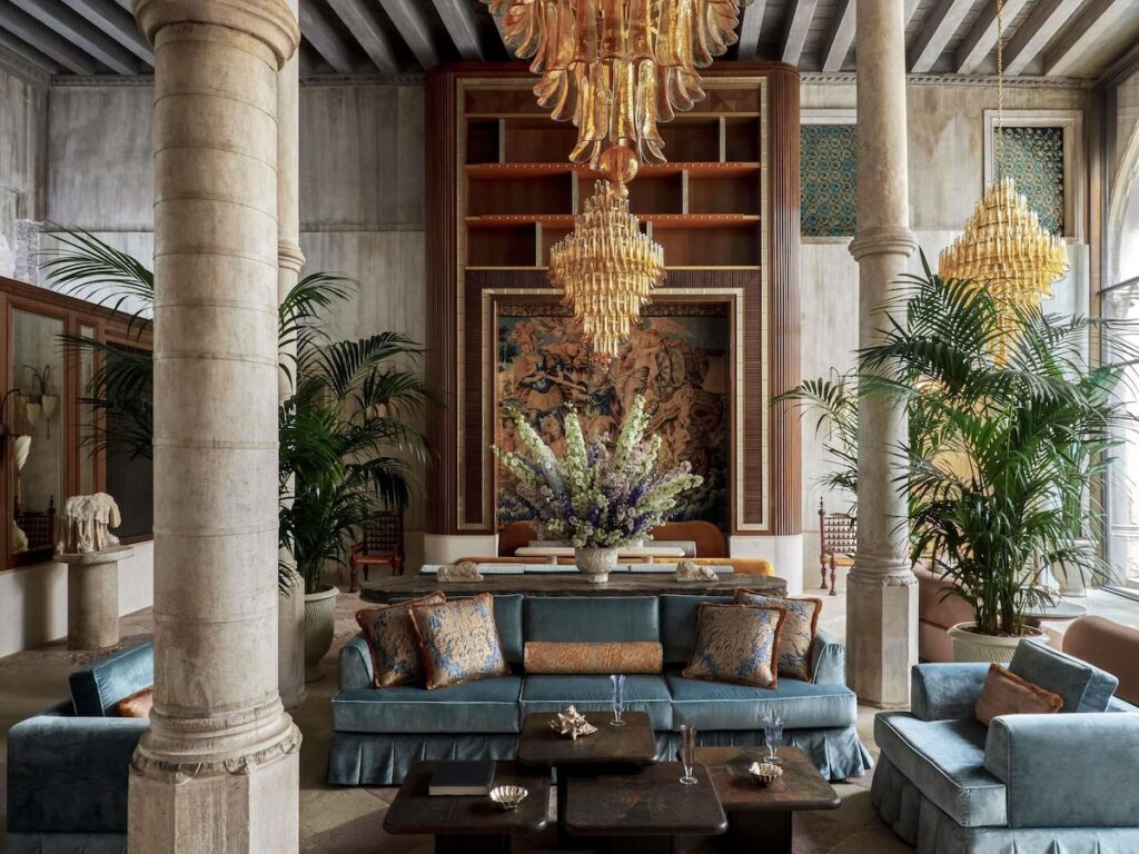 Lobby do Orient Express Venezia com colunas clássicas, sofá em veludo e lustre de Murano, referência entre os hotéis de Veneza.