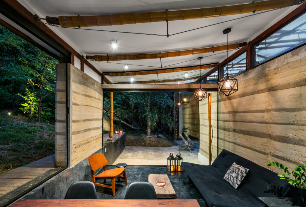 Estar da Casa de hóspedes em Paraty com vigas de bambu e taipa, unindo design de interiores e arquitetura vernacular.