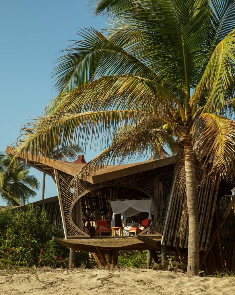 Casulo elevado em bambu no Hotel Playa Viva entre palmeiras, ícone sustentável de arquitetura vernacular.