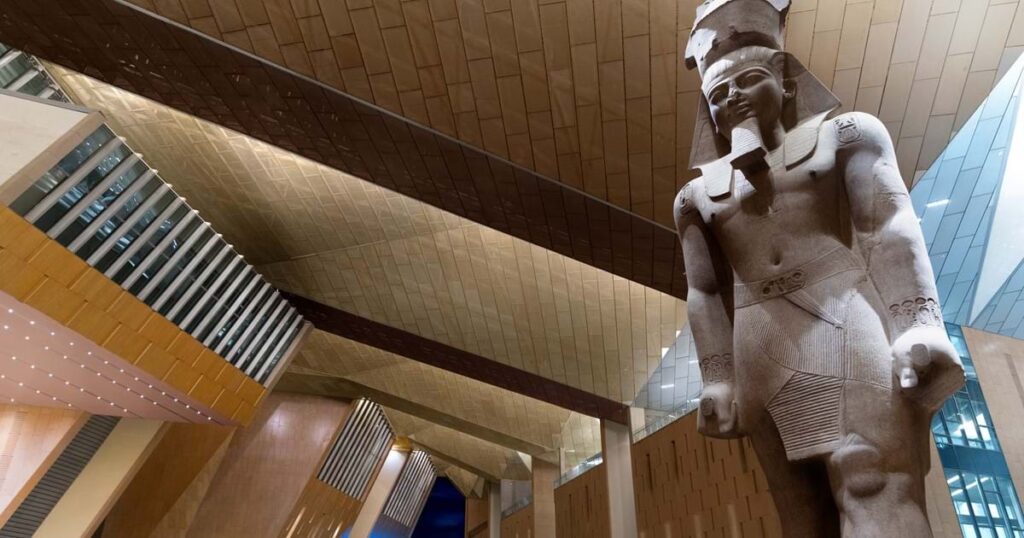Colossal estátua de Ramsés II no átrio monumental de seis andares do Grand Egyptian Museum.