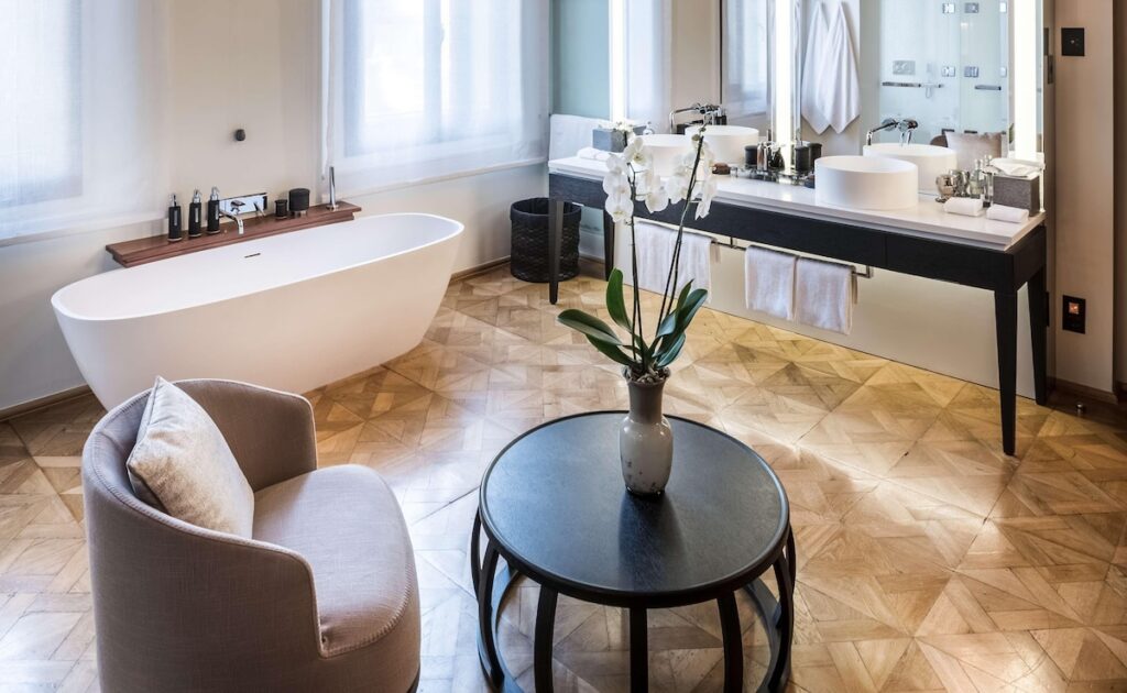 Banheiro contemporâneo do Aman Venice com banheira de imersão e piso em parquet, destaque nos hotéis de Veneza.