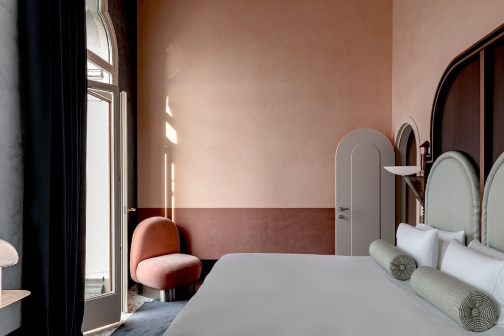 Quarto do Il Palazzo Experimental com cabeceira em arco e acabamento em marmorino, charme dos hotéis de Veneza.