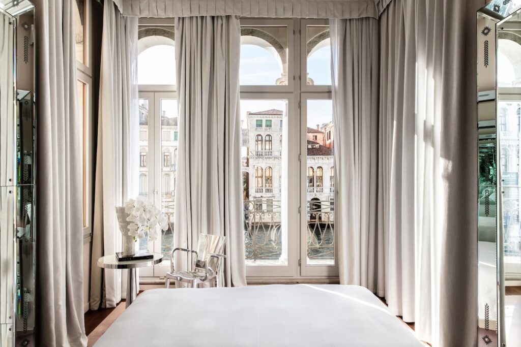 Suíte do Palazzina Grassi com colunas de espelho gravado e vista para o Grand Canal, luxo nos hotéis de Veneza.