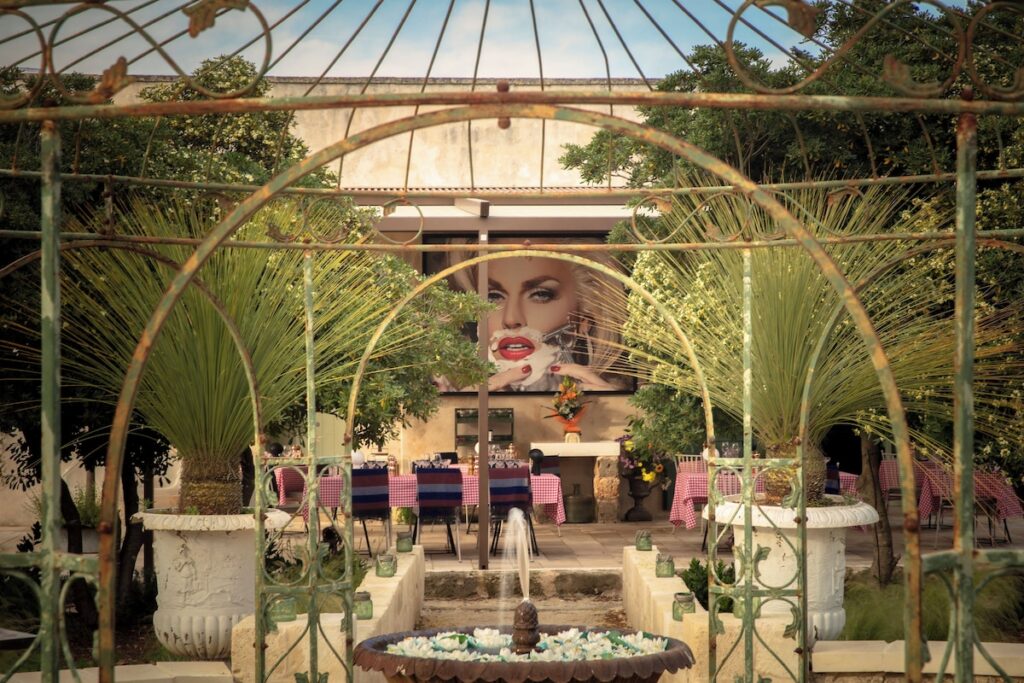 Área externa do restaurante no Castle Elvira com gazebo em ferro, fonte e arte pop, expressando a essência dos hotéis boutique na Púglia.
