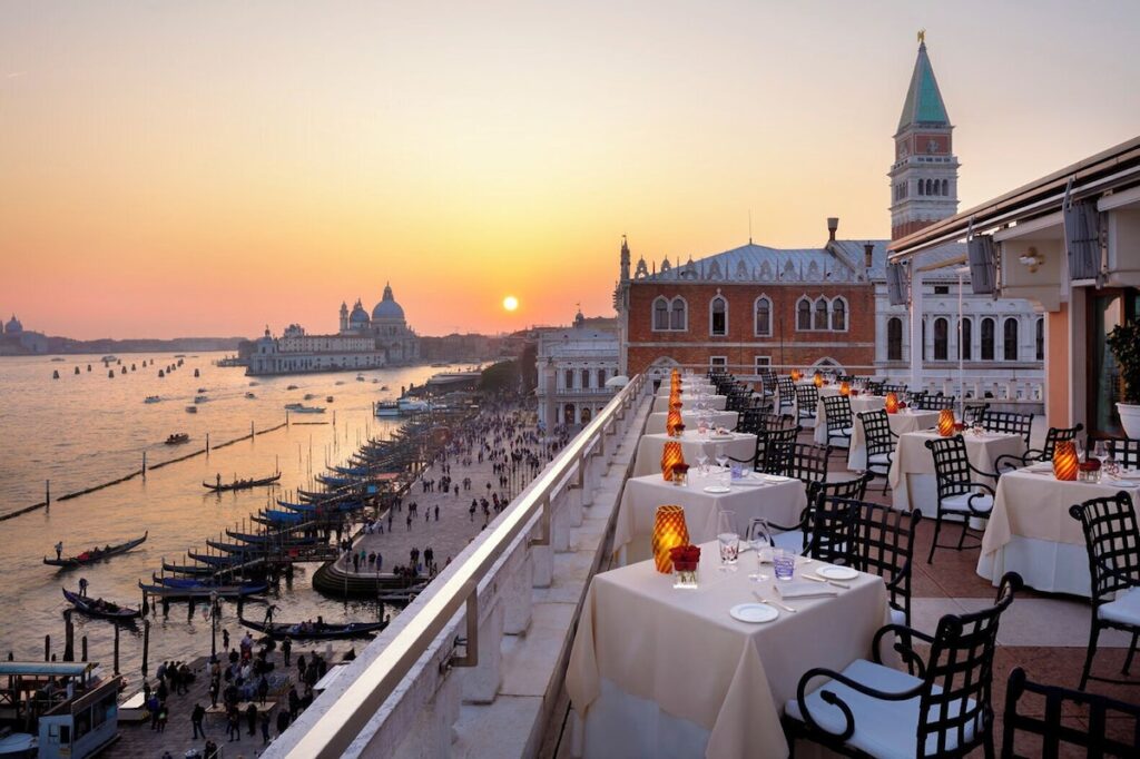 Terraço gastronômico do Hotel Danieli com vista panorâmica da lagoa ao pôr do sol, referência de sofisticação nos hotéis de Veneza.