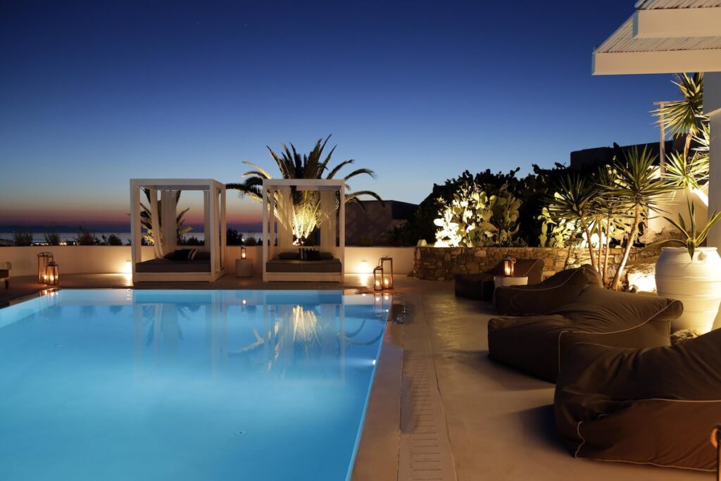 Área da piscina iluminada com cabanas e clima lounge no Livin Mykonos Hotel, sugestão de onde ficar em Mykonos.