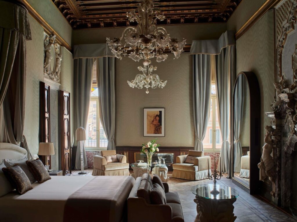 Suíte palaciana do Orient Express Venezia com teto em caixotão e lareira esculpida, destaque nos hotéis de Veneza.