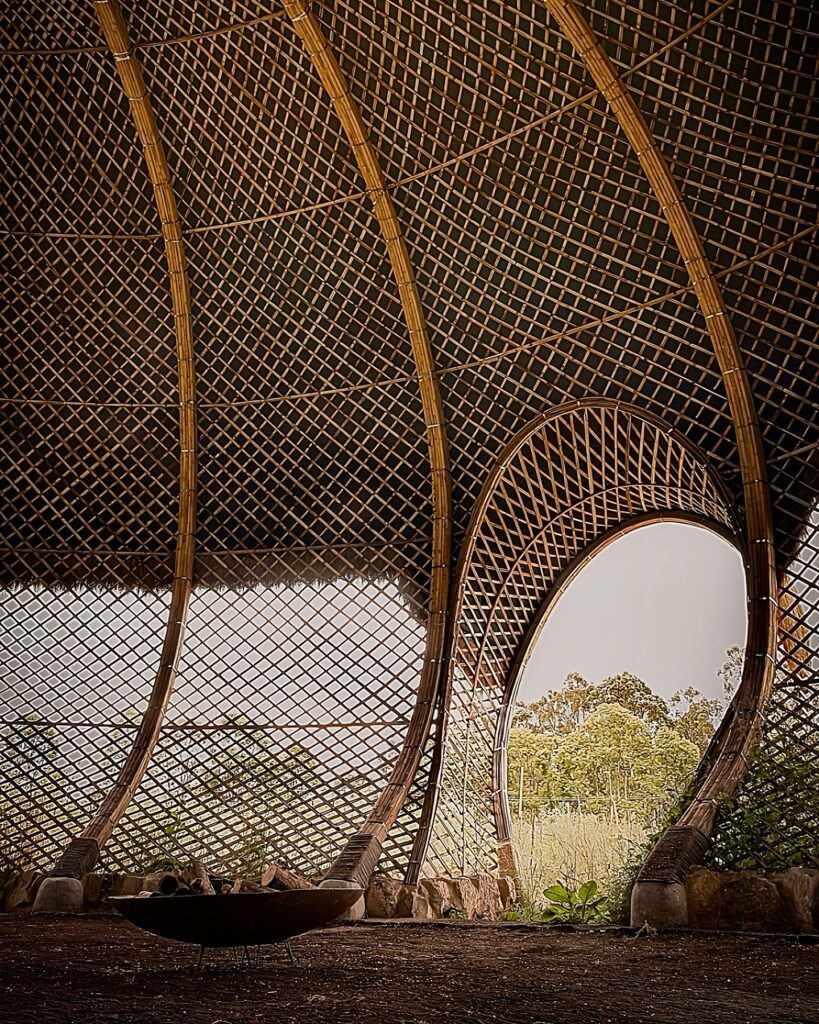 Interior da Casa de Pensamiento com portal em arco e malha de bambu, valorizando a arquitetura vernacular.