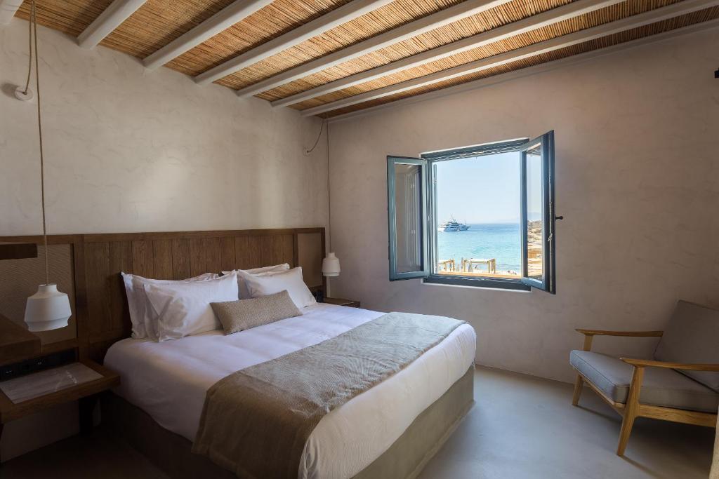 Quarto com cabeceira em madeira e janela aberta para o mar no Branco Mykonos, dica exclusiva de onde ficar em Mykonos.