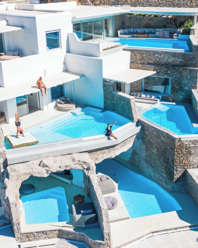 Piscinas infinitas em múltiplos níveis esculpidas na encosta do Cavo Tagoo, destaque de onde ficar em Mykonos.