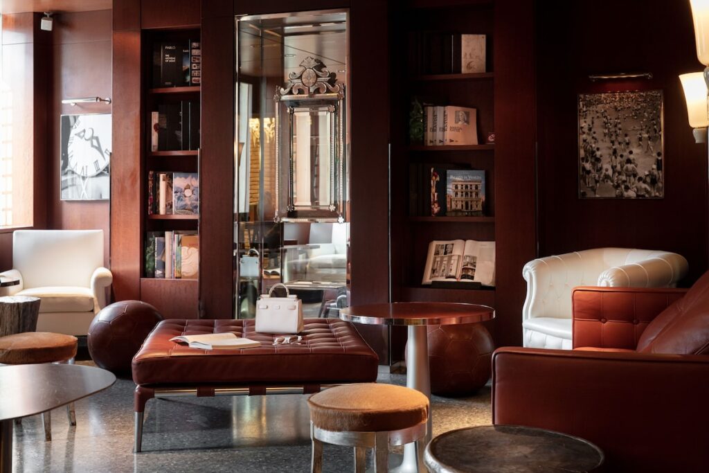 Biblioteca e lounge em madeira nobre com poltronas de couro no Palazzina Grassi, requinte dos hotéis de Veneza.