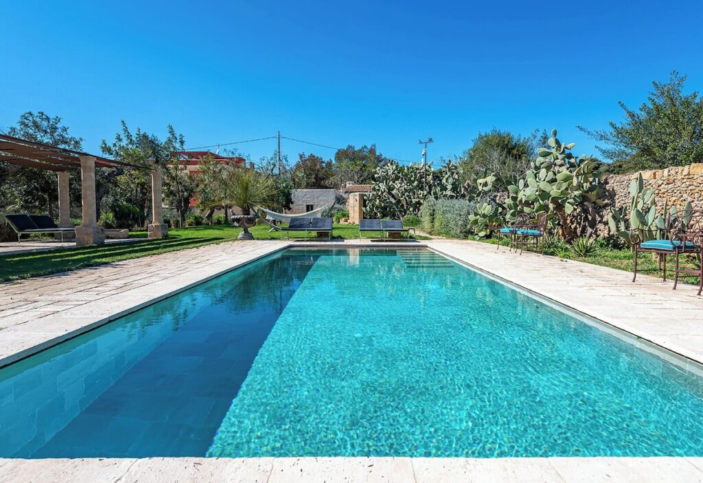 Piscina ao ar livre com deck em pedra calcária e vegetação mediterrânea no Castle Elvira, destaque de lazer em hotéis boutique na Púglia.