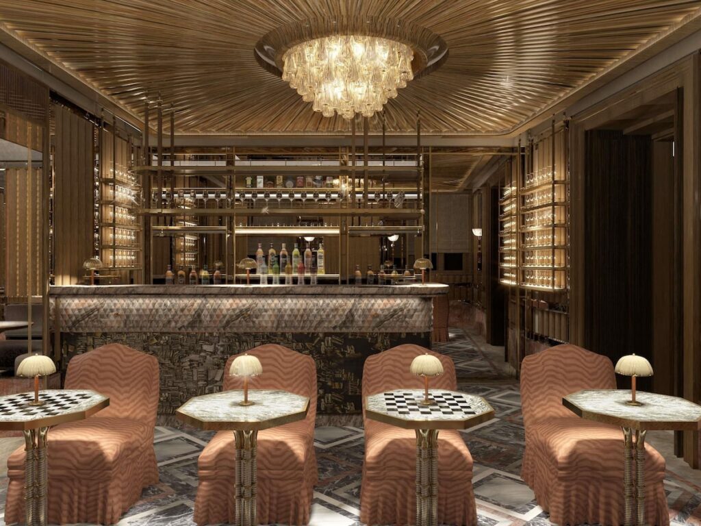 Bar sofisticado do Orient Express Venezia com teto dourado e balcão em mármore, alta coquetelaria nos hotéis de Veneza.