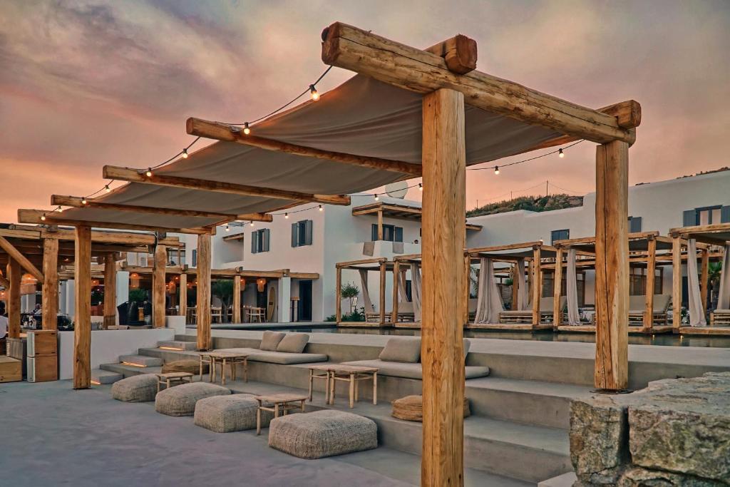 Área de estar externa em degraus com pergolados rústicos e iluminação cênica no Branco Mykonos, onde ficar em Mykonos.