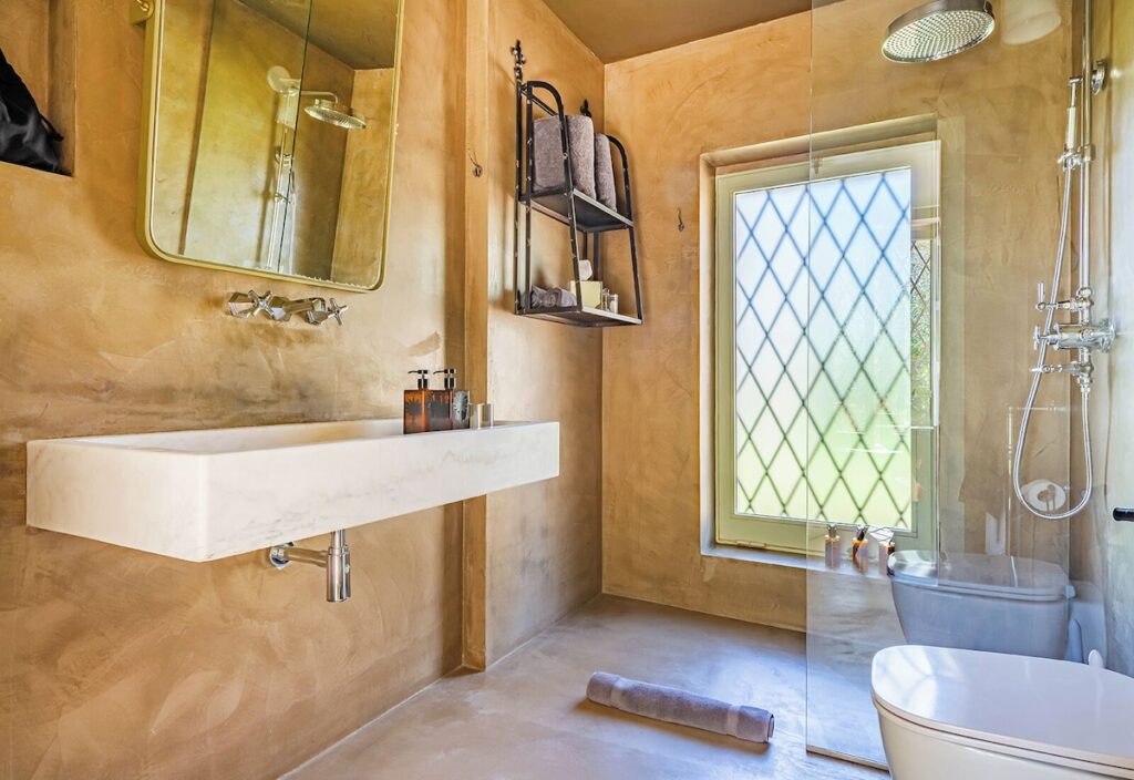 Banheiro em microcimento ocre e mármore esculpido na casa de campo do Castle Elvira, exemplo de design em hotéis boutique na Púglia.