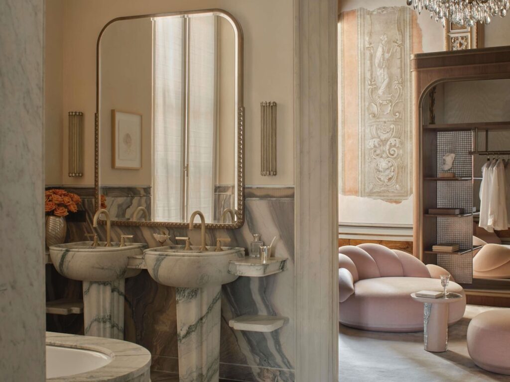 Banheiro em mármore esculpido e antessala com afresco no Orient Express Venezia, luxo autêntico nos hotéis de Veneza.