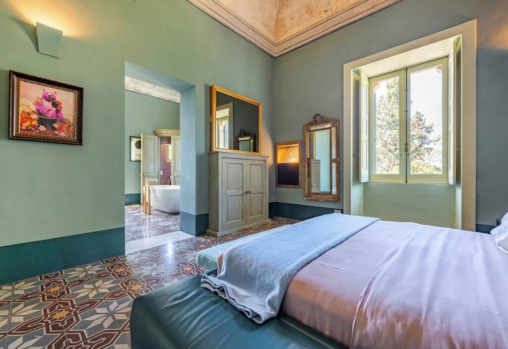 Quarto Casal Executivo no Castle Elvira com piso histórico em cementine e paredes verde-sálvia, charme de hotéis boutique na Púglia.