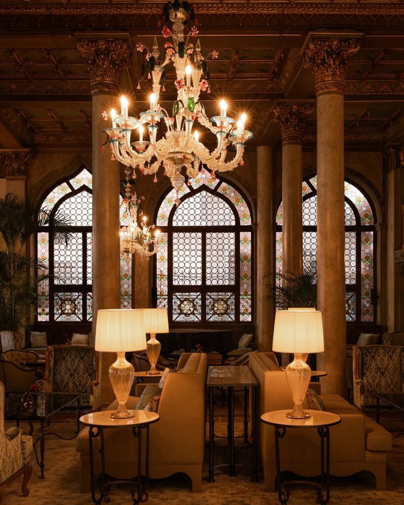 Salão nobre do Hotel Danieli com colunas de mármore, vitrais góticos e lustre de Murano, ícone dos hotéis de Veneza.