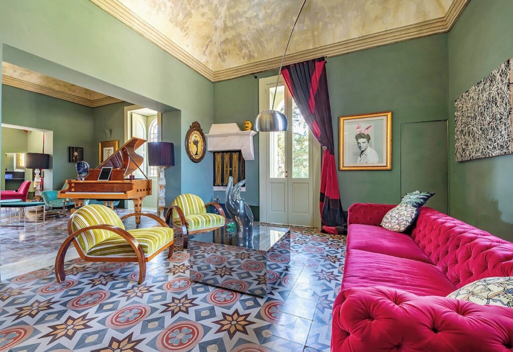 Salão principal do Castle Elvira com piano Bechstein, sofá magenta e afrescos históricos, ícone entre hotéis boutique na Púglia.
