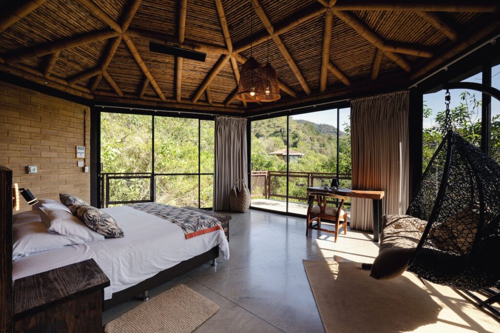 Suíte do Cannúa Lodge Hotel com teto cônico em bambu e paredes de terra, celebrando a arquitetura vernacular.