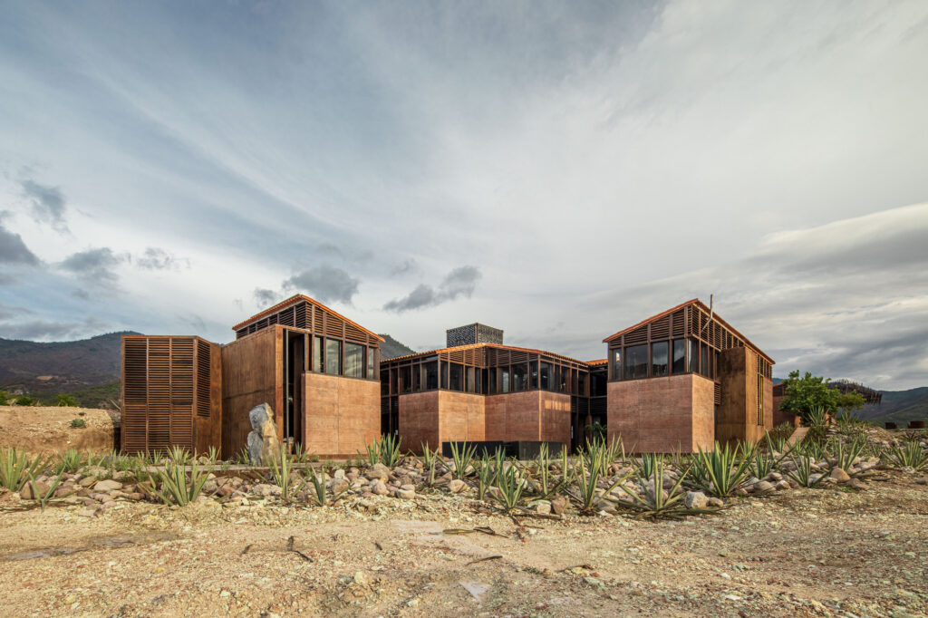 Fachada em terra compactada e madeira na Casa Silencio, exemplar de arquitetura vernacular contemporânea em meio à paisagem árida.