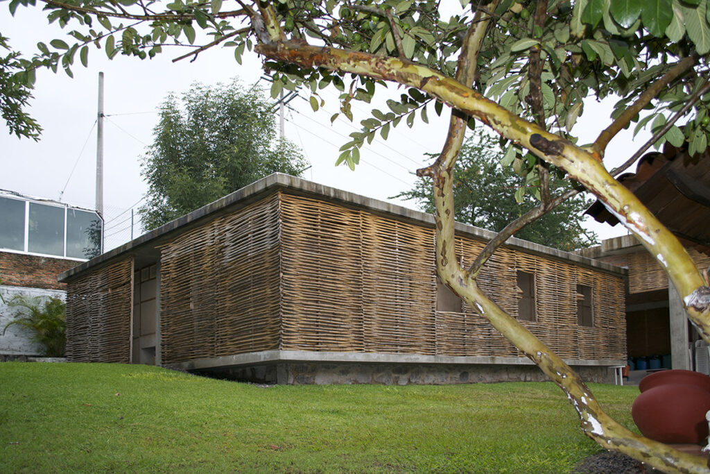 Edifício comunitário com paredes de bahareque e celosias de carrizo, redefinindo a arquitetura vernacular.