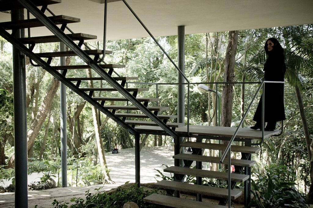 Escadaria metálica suspensa e pilotis na Casa de Vidro, obra modernista icônica de Lina Bo Bardi em São Paulo.