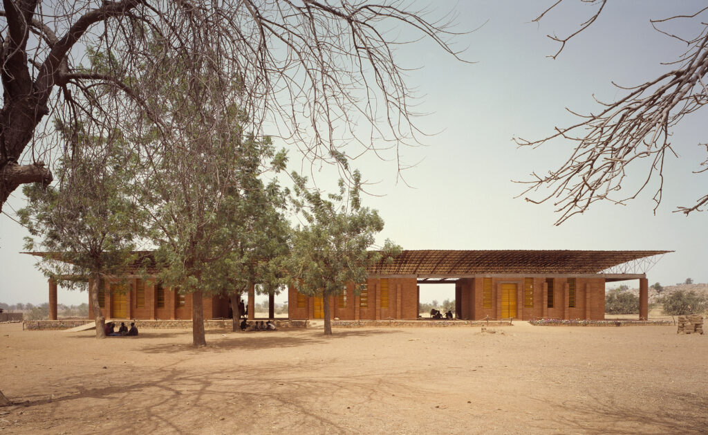Vista externa da Escola Primária em Gando de Kéré Architecture, integrando cobertura flutuante e arquitetura vernacular.